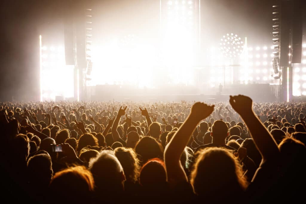 A lot of people raised up hands at the concert event. Fans arms against the stage light
