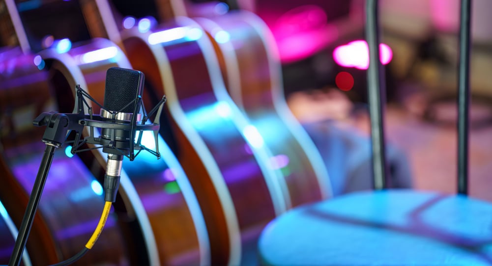 A stage microphone is set up amongst a variety of acoustic guitars.