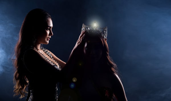 Two Miss Asian Women Pageant Beauty Contest in Evening Ball Gown dress wearing silver diamond crown on head sash, waiting final announcement moment, dark smoke background low key exposure silhouette