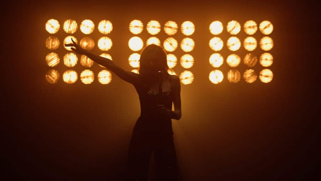 Silhouette of sensual girl musician singing microphone in studio lights. The Star Vocal Competition