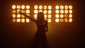 Silhouette of sensual girl musician singing microphone in studio lights. The Star Vocal Competition