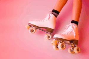 Roller skates and girl's legs on pastel pink - sports equipment and recreation