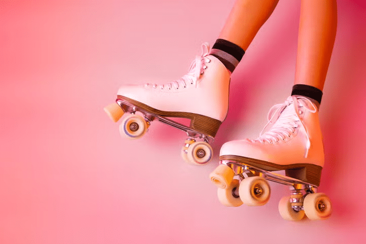 Roller skates and girl's legs on pastel pink - sports equipment and recreation